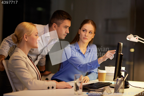 Image of business team with computer working late at office