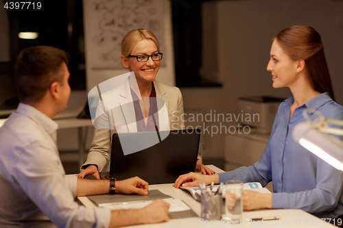Image of business team with laptop working late at office