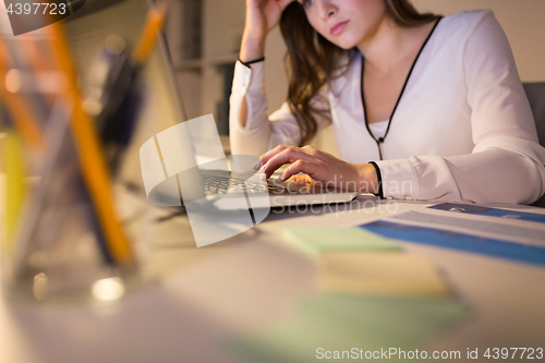 Image of businesswoman with laptop working at night office