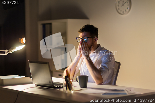 Image of tired businessman with laptop at night office
