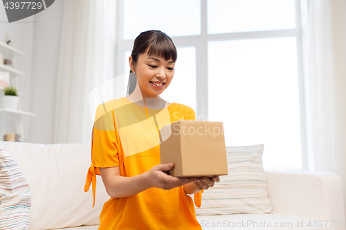 Image of happy asian young woman with parcel box at home