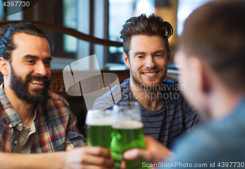 Image of male friends drinking green beer at bar or pub