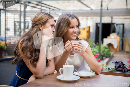 Image of smiling young women drinking coffee at street cafe