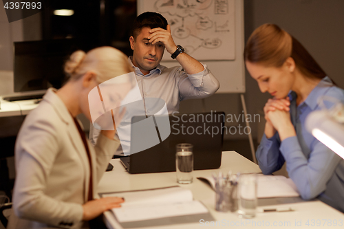 Image of business team with laptop working late at office