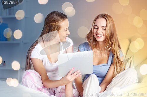 Image of happy friends or teen girls with tablet pc at home