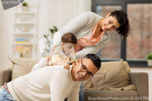 Image of happy family and baby daughter playing at home