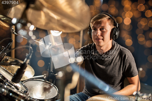 Image of musician playing drum kit at concert over lights