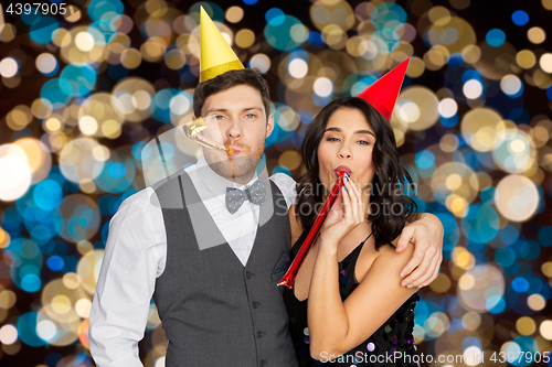 Image of happy couple with party blowers having fun