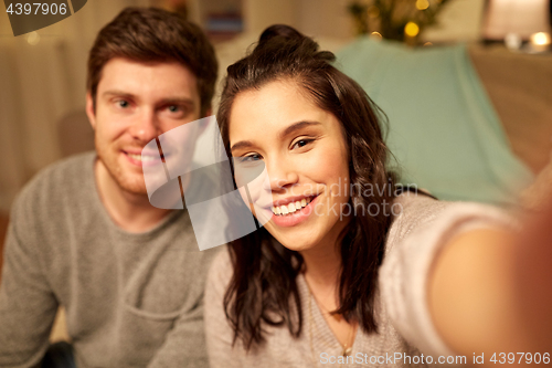 Image of happy couple taking selfie at home