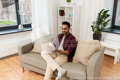 Image of man in earphones listening to music on smartphone