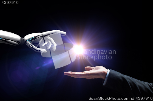 Image of robot and human hand flash light over black