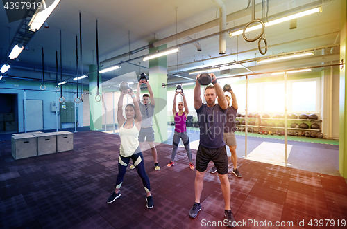 Image of group of people with kettlebells exercising in gym