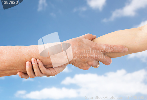 Image of close up of senior and young woman holding hands