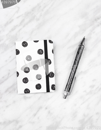 Image of Black and white diary and pen on marble background