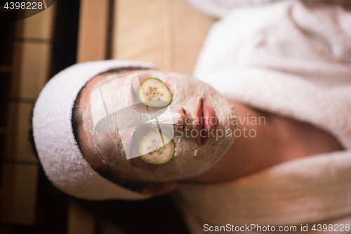 Image of woman is getting facial clay mask at spa