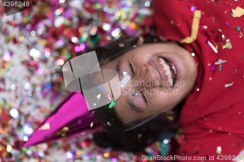 Image of kid blowing confetti while lying on the floor