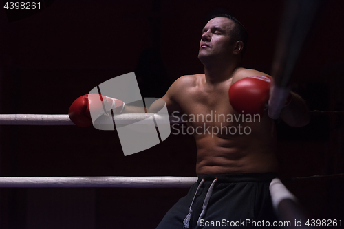 Image of kick boxer resting on the ropes in the corner