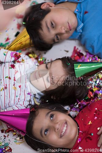 Image of kids  blowing confetti while lying on the floor