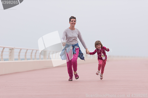 Image of mother and cute little girl on the promenade by the sea