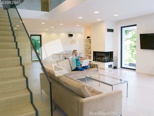 Image of Young woman using laptop at home