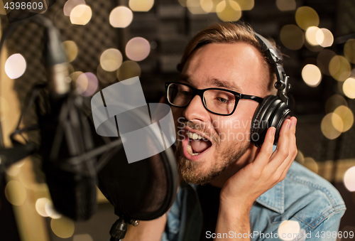 Image of man with headphones singing at recording studio