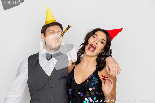 Image of happy couple with party blowers having fun