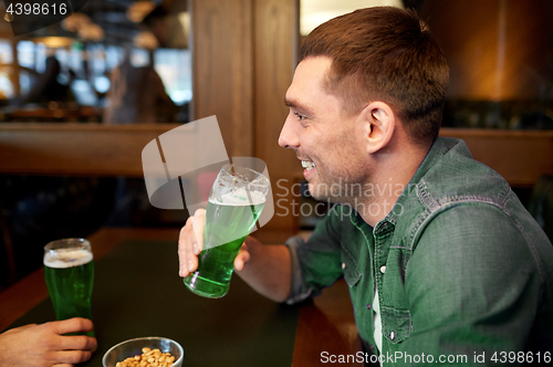 Image of man drinking green beer at bar or pub