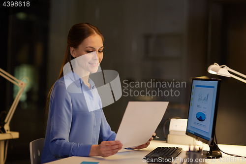 Image of businesswoman with papers working at night office