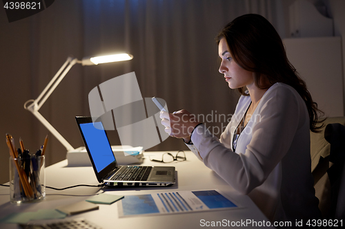 Image of businesswoman with smartphone and laptop at office