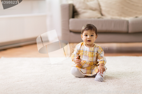 Image of happy smiling baby girl sitting on floor home