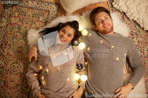 Image of happy couple with garland lying on floor at home
