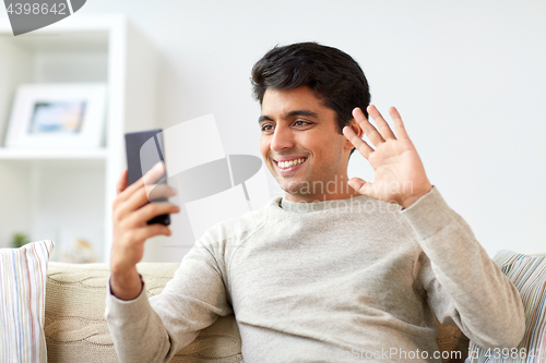 Image of happy man having video call on smartphone at home