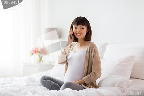 Image of happy pregnant woman calling on smartphone at home