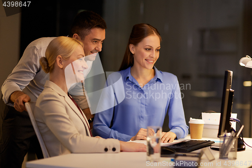 Image of business team with computer working late at office