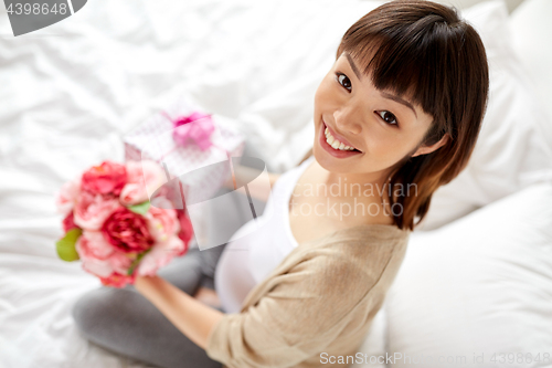 Image of happy asian pregnant woman with gift and flowers