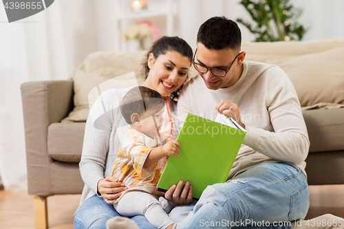Image of happy family with baby reading book at home