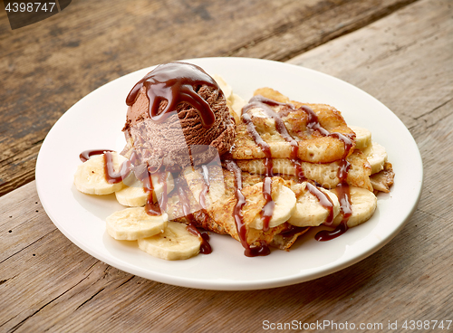 Image of Crepes with banana and chocolat icecream on wooden desk