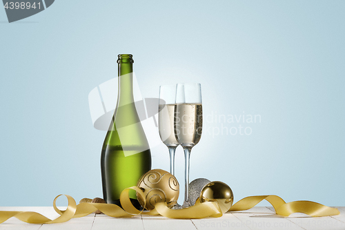 Image of Glasses with champagne and bottle over sparkling holiday background