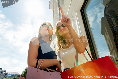 Image of happy women with shopping bags in city