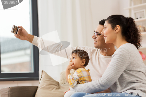 Image of mother and father with baby taking selfie at home