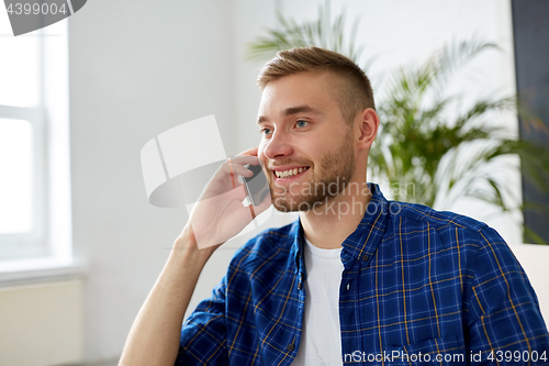 Image of smiling young man calling on smartphone at office