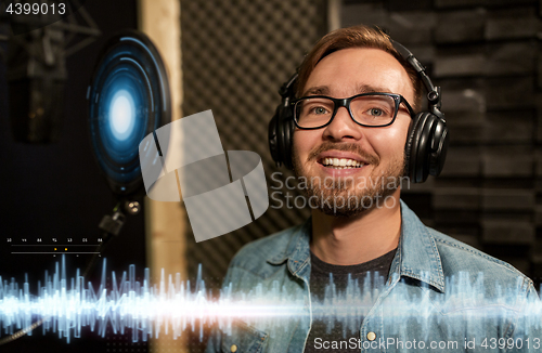 Image of man with headphones singing at recording studio