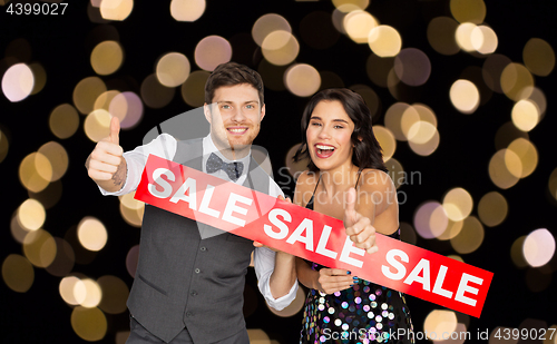 Image of happy couple with red sale sign showing thumbs up