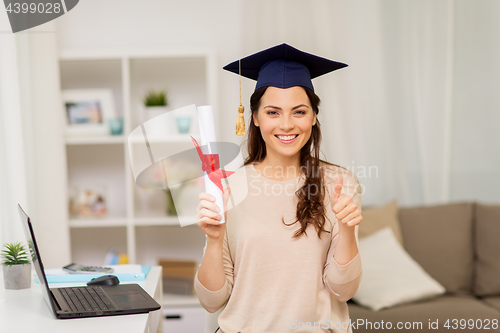 Image of student with diploma at home showing thumbs up