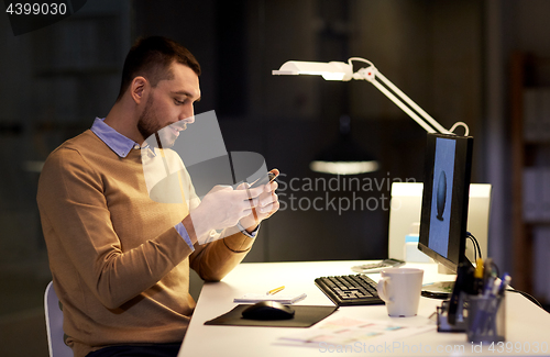 Image of man with smartphone working late at night office