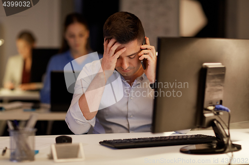 Image of businessman calling on sartphone at night office