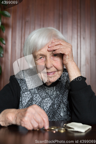 Image of Elderly woman sitting at the table counting money in her wallet.