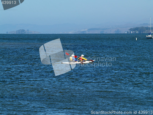 Image of two-man kayak on bay with moored sailboat