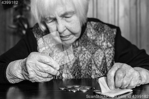 Image of Elderly woman sitting at the table counting money in her wallet.