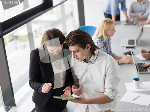 Image of Two Business People Working With Tablet in office